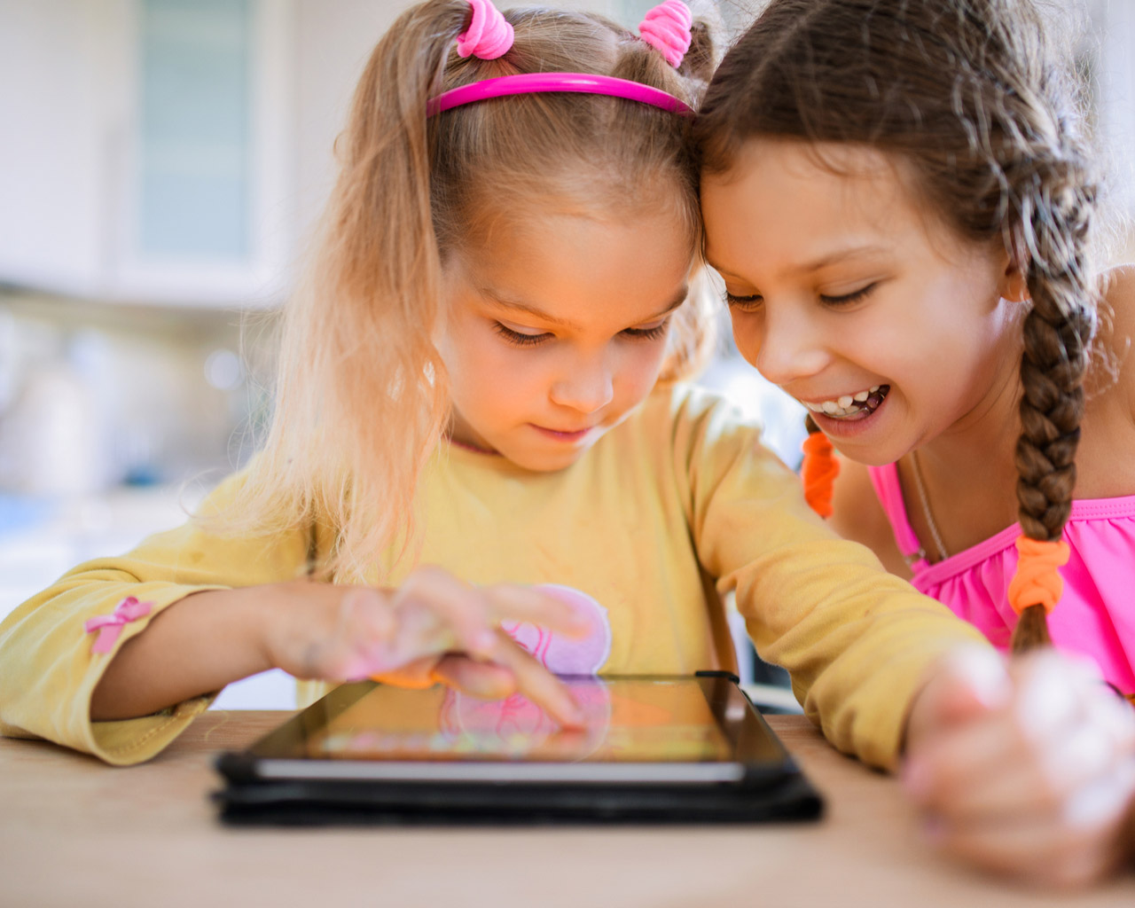 Two children play happily on a tablet